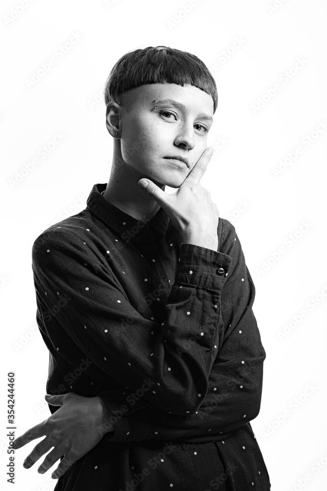 Black and white portrait of a young hipster woman with short hair, looking straight in a camera, hands holding her chin, determined and confident look Black and white portrait of a young hipster woman with short hair, looking straight in a camera, hands holding her chin, determined and confident look