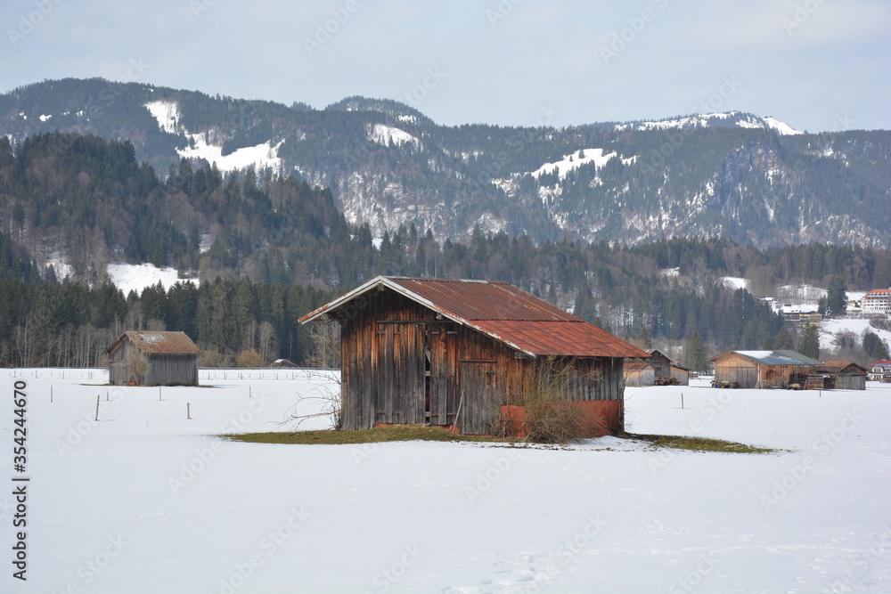 Braune Scheune mit rostigem Dach im Winter im Schnee bei Oberstdorf in Bayern