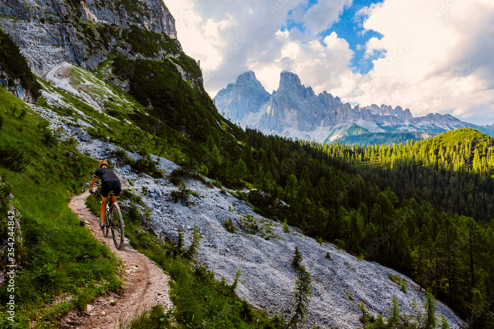 Cycling outdoor adventure in Dolomites. Cycling woman in Dolomites landscape. Woman cycling MTB enduro trail track. Outdoor sport activity.