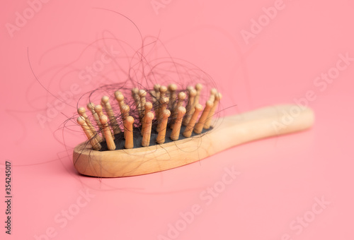 Obraz na płótnie Black hair loss problem with hairbrush on pink background