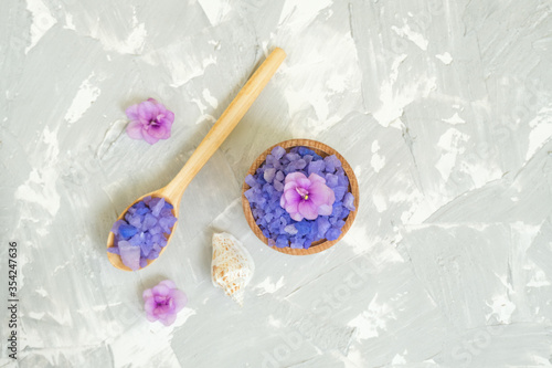 Wooden spoon and bowl with purple sea salt on grey background.Background for advertising salty.
