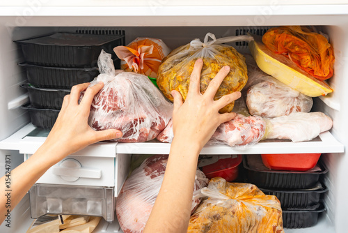 Foto A woman takes out and puts frozen food in a freezer for long storage