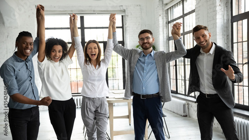 Fotografía Excited diverse business people celebrating success, holding raised hands, looki
