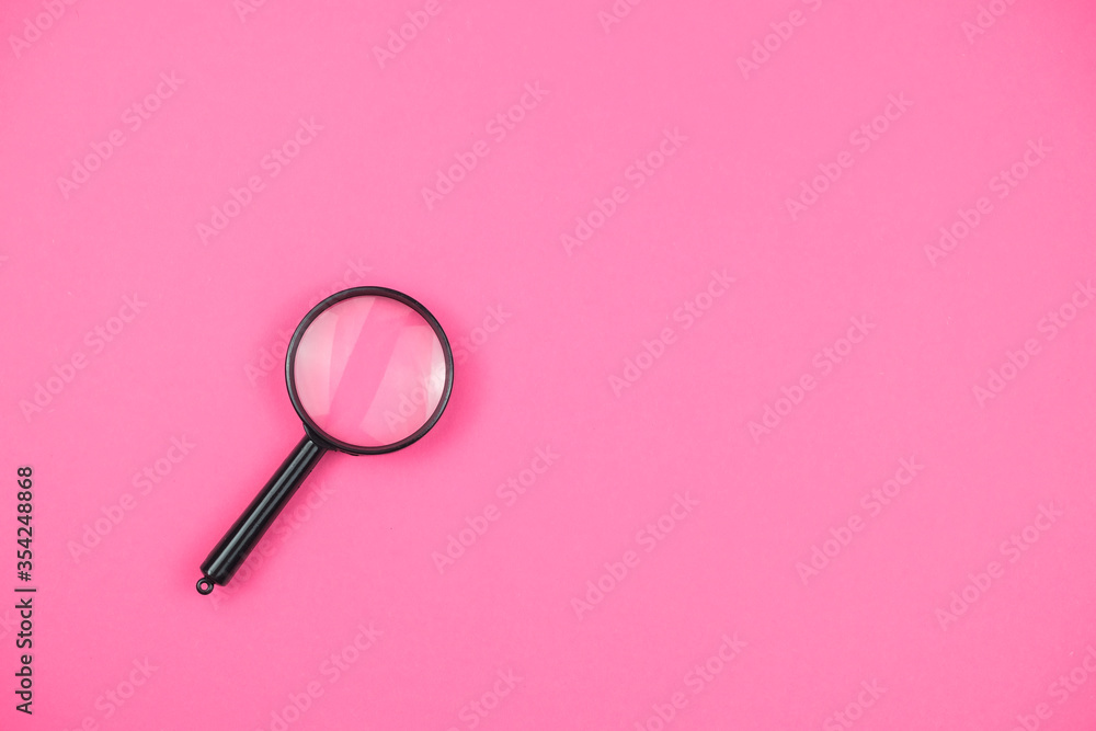 Magnifier on the pink background, close up Magnifier on the pink background, close up