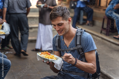 caucasian man eats street food in Sri Lankan market