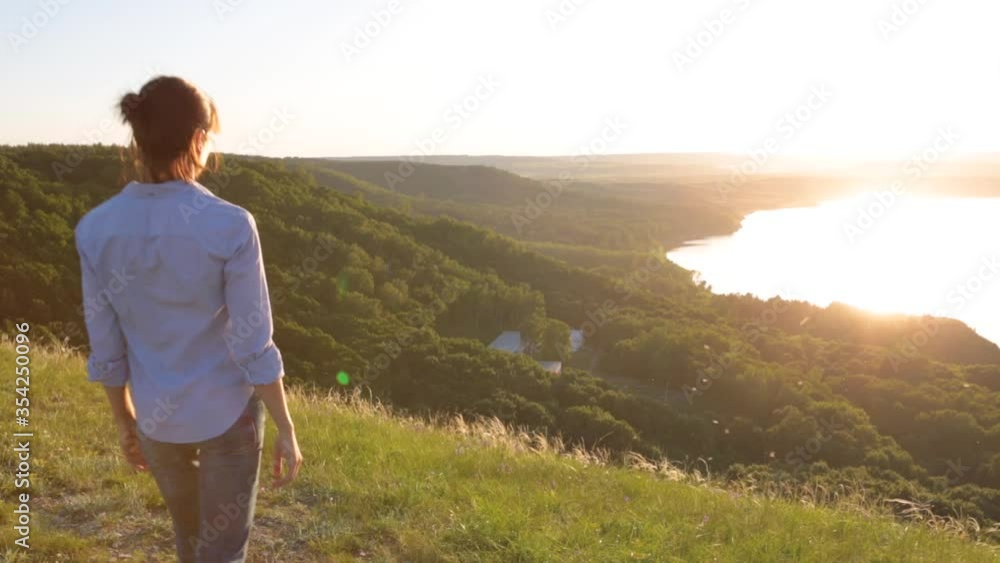 Girl on the background of a mountain lake, sea or ocean raises her hands above and enjoys the feeling of freedom at sunset Girl on the background of a mountain lake, sea or ocean raises her hands above and enjoys the feeling of freedom at sunset