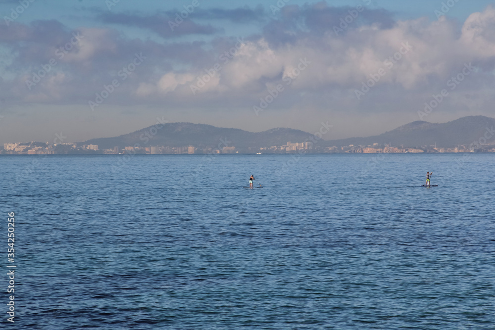 Two people are sailing in the sea on a surfboard. Mallorca, Spain. Balearic Islands