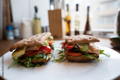 Fresh salmon sandwich with salad close up and avocado and a white plate