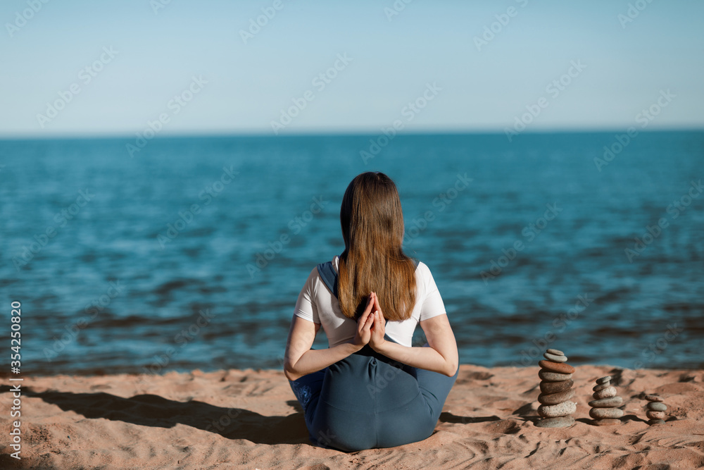 The girl does yoga on the shore of the lake.