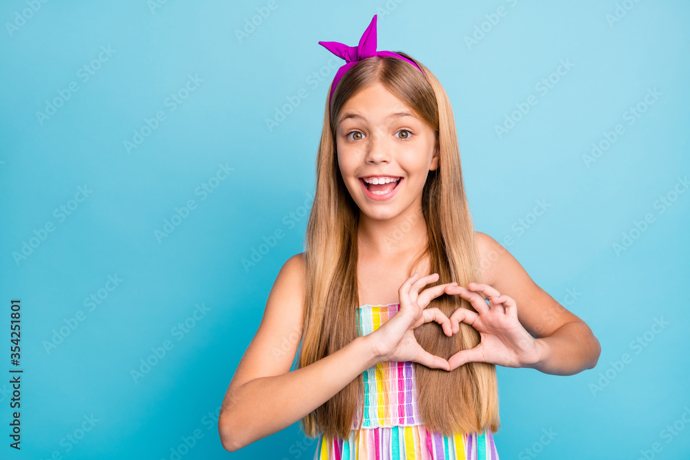 Portrait of amazed energetic cheerful kid girl make heart shape finger demonstrated cupid love symbol chest wear trendy clothes isolated over blue color background Portrait of amazed energetic cheerful kid girl make heart shape finger demonstrated cupid love symbol chest wear trendy clothes isolated over blue color background