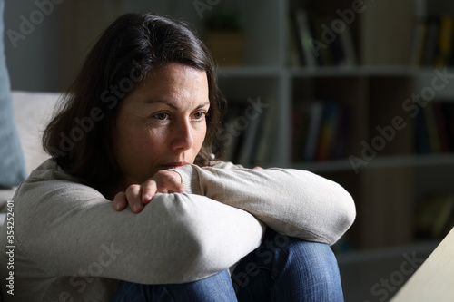 Bild auf Leinwand Pensive adult woman looking away thinking at night at home
