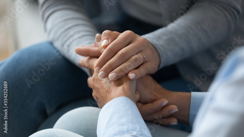 Adult daughter comforting old mom strokes holds her hand close up view. Strong connection confidential conversation, empathy and mercy, support in hard life period, be near sharing heart pain concept photo