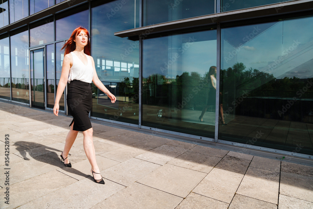 Naklejka premium Young redhead business woman in formal outside