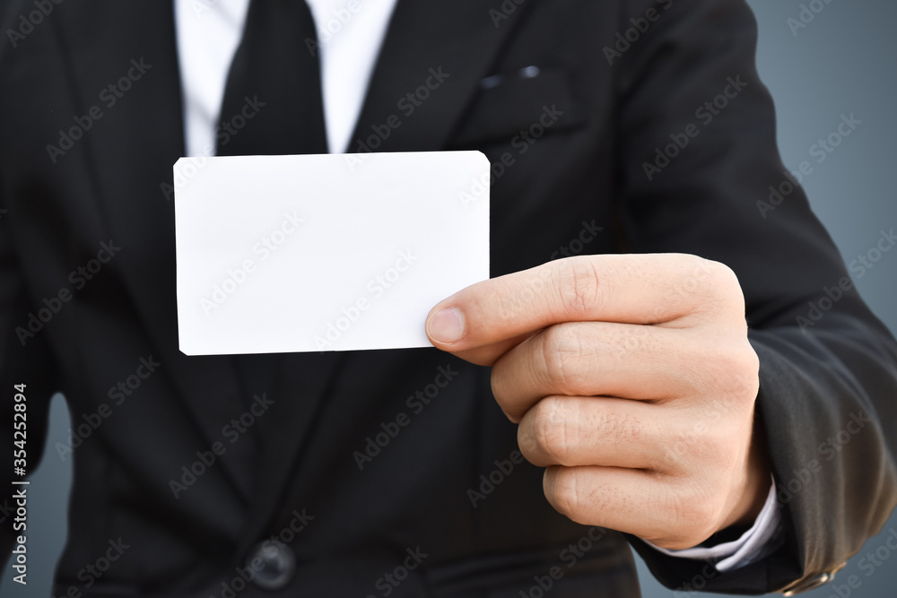 Closeup of businessman showing white piece of paper in black suit. Idea for business credit card or visiting card. Closeup of businessman showing white piece of paper in black suit. Idea for business credit card or visiting card.