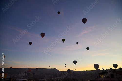 Cappadocia, Turkey - December 20, 2019: Many hot air balloons flying in blue sky with white clouds over rock landscape at Cappadocia Turkey in mornignt in sinrise, Attraction for tourists in Goreme