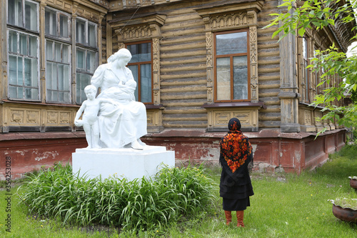 Russian girl in vintage traditional national Pavlovo Posad shawl, scarf. Sokolikov wooden house, Pavlovsky Posad town, Moscow region, Russia. Russian folk style in architecture, architectural fashion photo