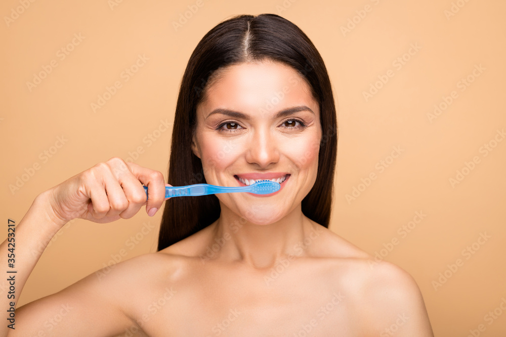 Close up photo of attractive latin naked lady holding blue tooth brush cleaning white teeth use new menthol paste isolated beige pastel color background Close up photo of attractive latin naked lady holding blue tooth brush cleaning white teeth use new menthol paste isolated beige pastel color background