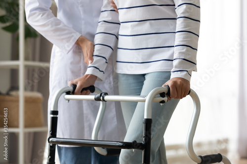 Canvas Print Cropped image caregiver helping to disabled patient walking with rollator equipment reduce load and joint pain with arthritis