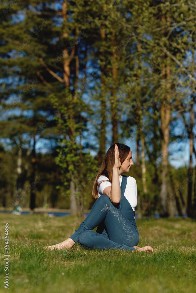 Woman practicing yoga pose in the forest nature. Playing sports on the grass in the woods Woman practicing yoga pose in the forest nature. Playing sports on the grass in the woods