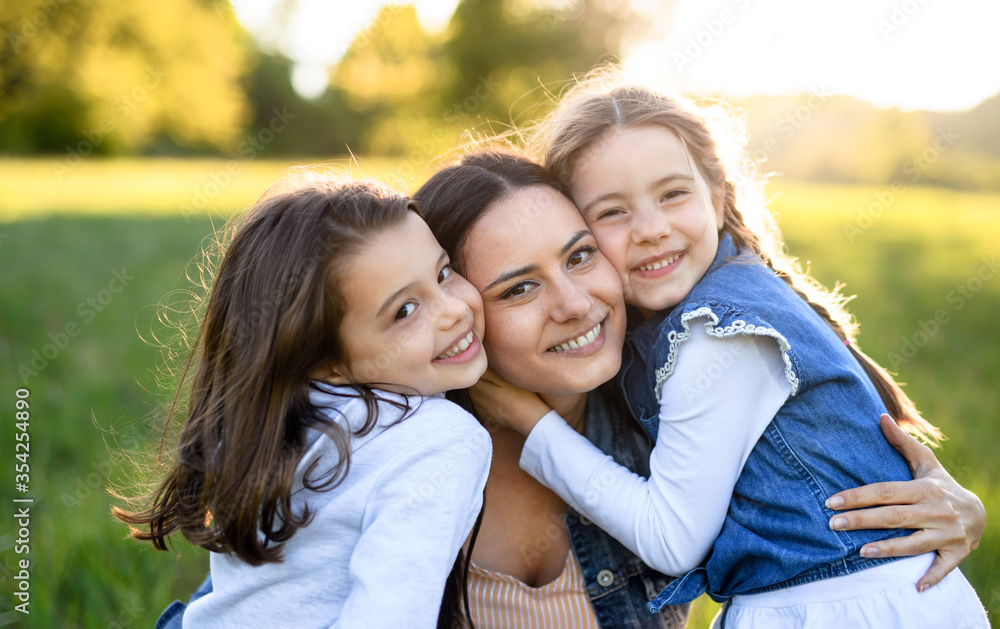 Mother with two small daughters having fun outdoors in spring nature, hugging. Mother with two small daughters having fun outdoors in spring nature, hugging.