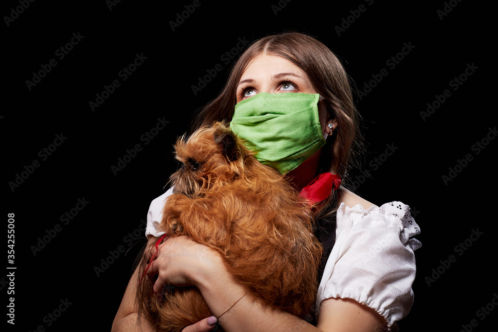 Girl in protective medical green mask and national ethnic dress holding small dog in her hands. Coronavirus, COVID-19 pandemic concept. Domestic animal allergy, sneezing and coughing near of pets Girl in protective medical green mask and national ethnic dress holding small dog in her hands. Coronavirus, COVID-19 pandemic concept. Domestic animal allergy, sneezing and coughing near of pets