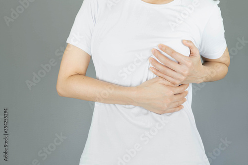 Woman hand checking lumps on her breast for signs of breast cancer on gray background, healthy lifestyle concept,healthy girl medical awareness cancer prevention concept
