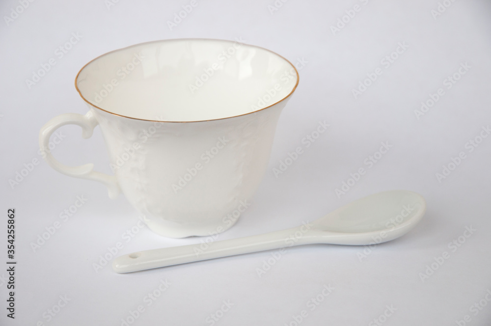 White porcelain cup and spoon on a white background White porcelain cup and spoon on a white background