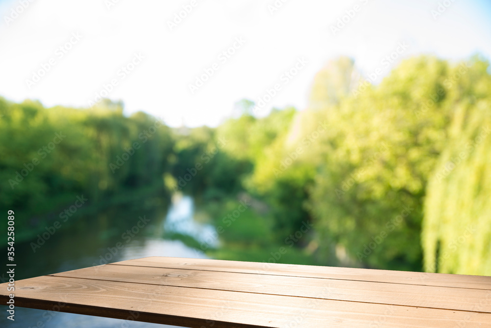 Empty wooden deck table with park bokeh background. Empty wooden deck table with park bokeh background.