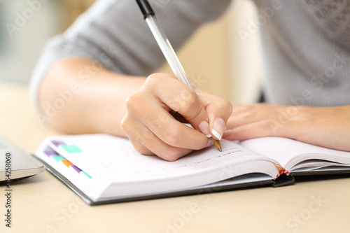 Woman hands writing notes on agenda on a desk