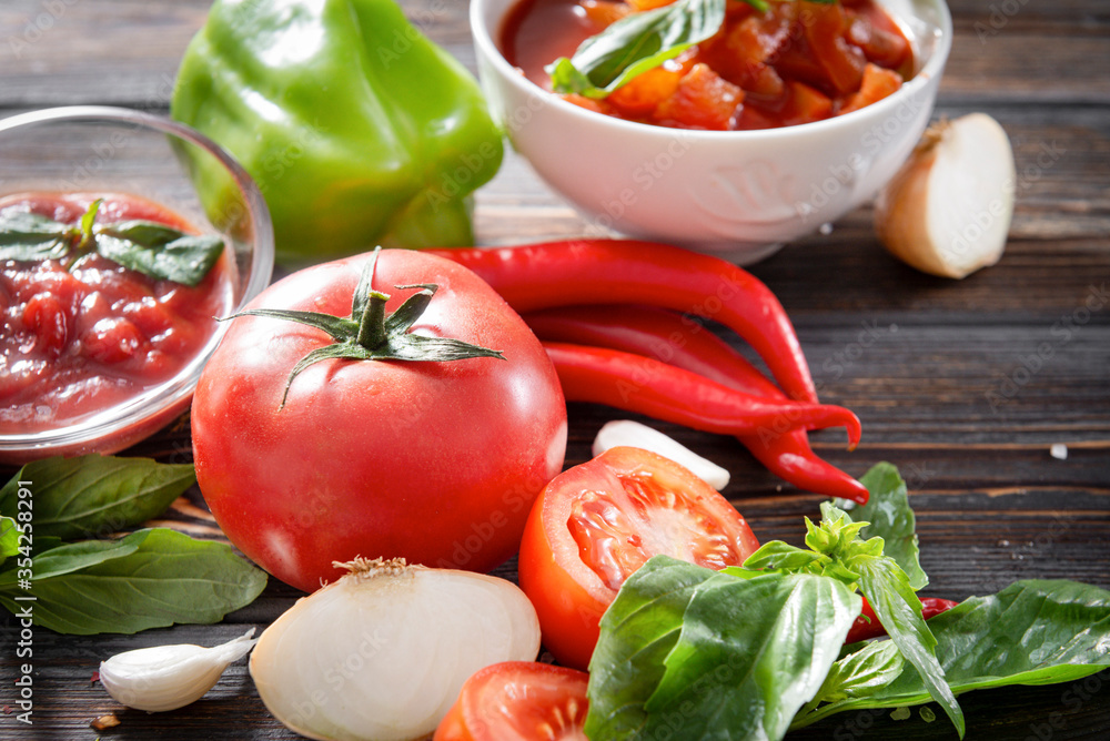 vegetable sauce, Lecho, ketchup with a sprig of green Basil, fresh tomato, red chili pepper, garlic, onion, sweet green pepper on a brown wooden vegetable sauce, Lecho, ketchup with a sprig of green Basil, fresh tomato, red chili pepper, garlic, onion, sweet green pepper on a brown wooden