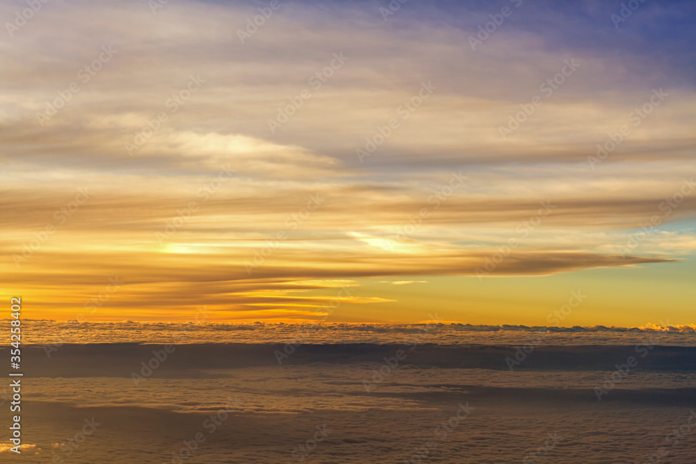 Panorama view of fluffy clouds on sunset sky view from flying airplane