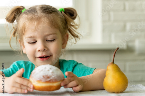 little girl chooses a donut instead of a pear. problems in baby food. obesity in children