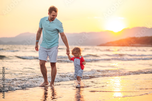  dad with little daughter walk on the beach at sea on vacation, concept happy fathers day, space for text