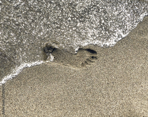 Obraz na plátně Footprint on sand washing out by sea wave close-up