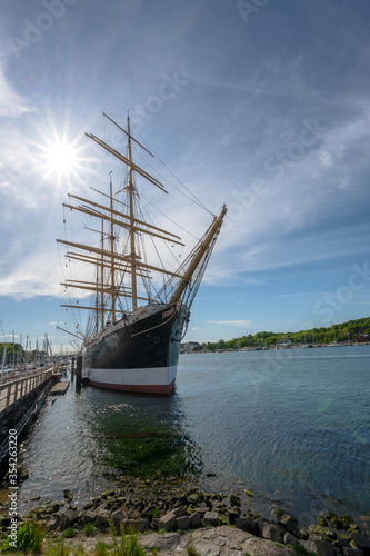 Museum ship Passat in the marina port of Travemuende, German four-masted steel barque, one of sailing ships Flying P-Liners. Blue sky with clouds and sun star, copy space