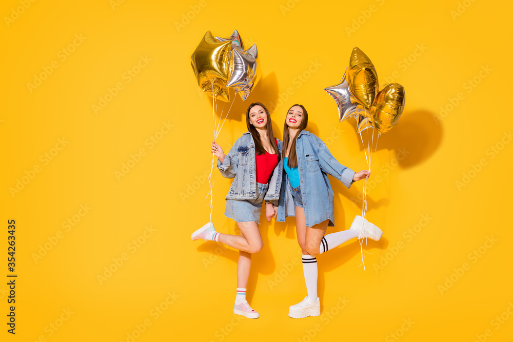 Full length body size view of nice attractive lovely slender cheerful cheery girls holding in hands air balls dancing having fun isolated on bright vivid shine vibrant yellow color background Full length body size view of nice attractive lovely slender cheerful cheery girls holding in hands air balls dancing having fun isolated on bright vivid shine vibrant yellow color background