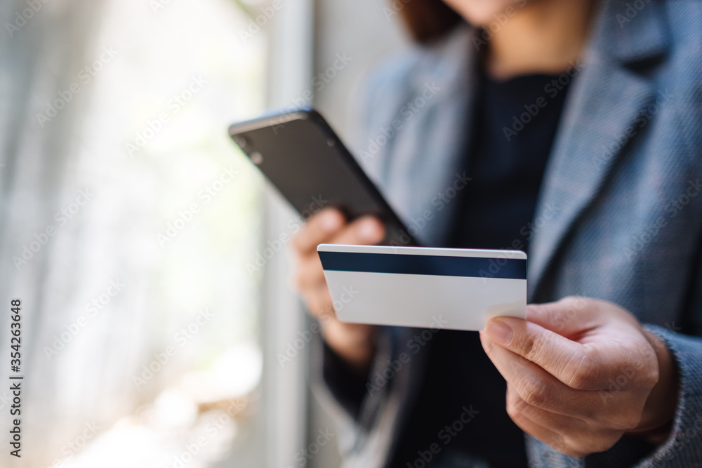 Closeup image of a woman using credit card for purchasing and shopping online on mobile phone Closeup image of a woman using credit card for purchasing and shopping online on mobile phone