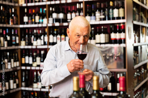 Fotografie Elderly man smells the quality of red wine