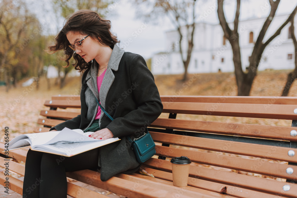 Pretty woman sitting with coffee abd book outdoors Pretty woman sitting with coffee abd book outdoors