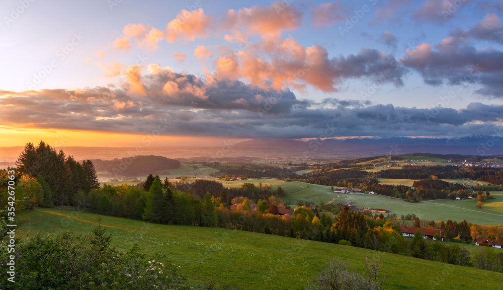 Colorful sunrise in rural landscape with fields, forest, houses and hills. Allgäu, Bavaria, Germany