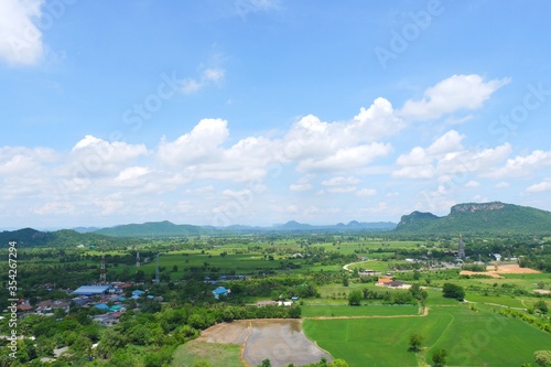 Green rice field with mountains under blue sky. The fields are grassy green.It's rainy season.Sky in the rainy season