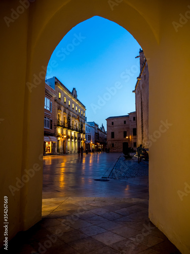 Obraz na plátně picturesque illuminated view in the dusk through an archway to the Placa de la C