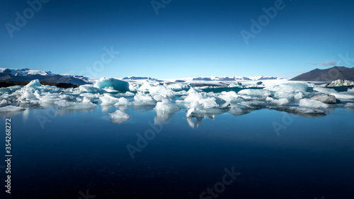 wide angle shot of ice floes floating in the cold calm water of the jökulsarlon lagoon in front of a huge icelandic glacier in the background