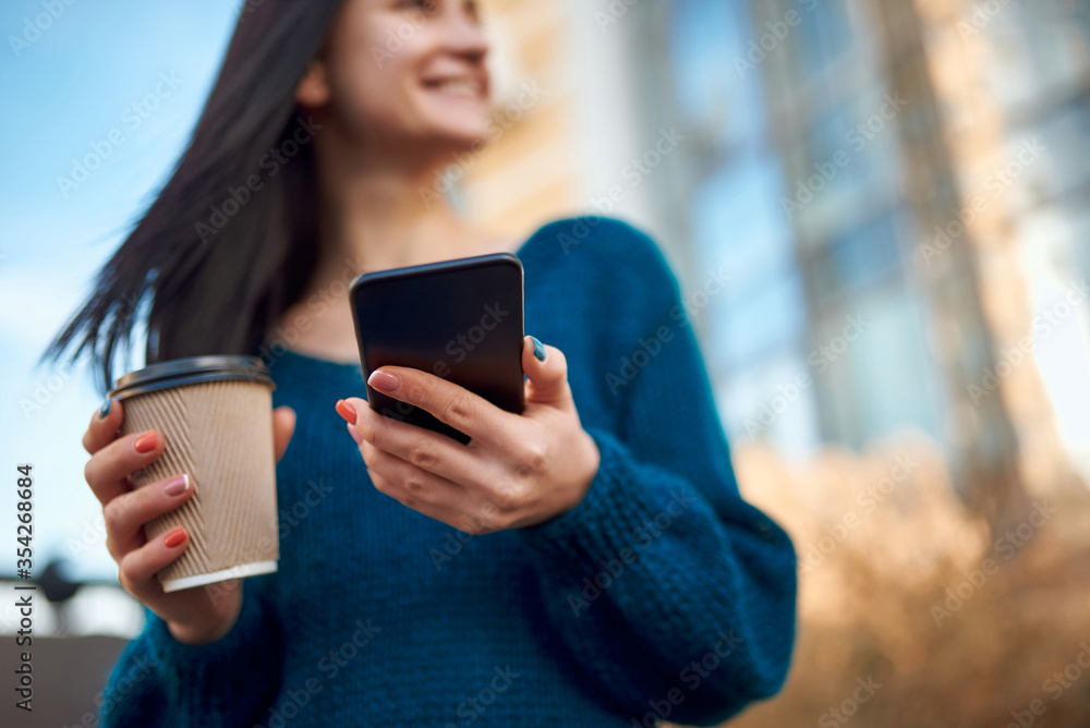Cropped shot of cup of drink and mobile phone in woman hands Cropped shot of cup of drink and mobile phone in woman hands