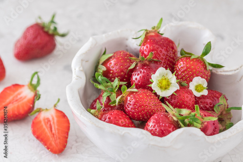 Handmade white pottery bowl with fresh strawberries on white background