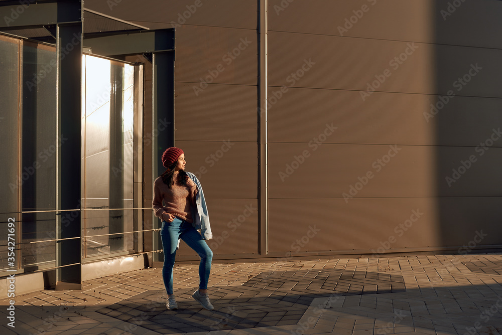 Stylish female standing in lights of a sun close to urban construction Stylish female standing in lights of a sun close to urban construction