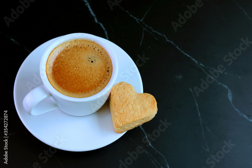 Cup of Espresso Coffee with a Heart Shaped Butter Cookie on Black Table