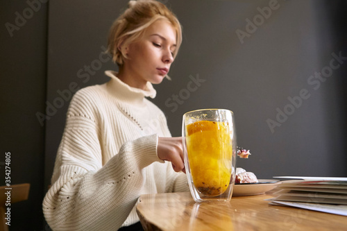 woman drinking hot tea while sitting at a table in a restaurant © Yehor Serdiuk