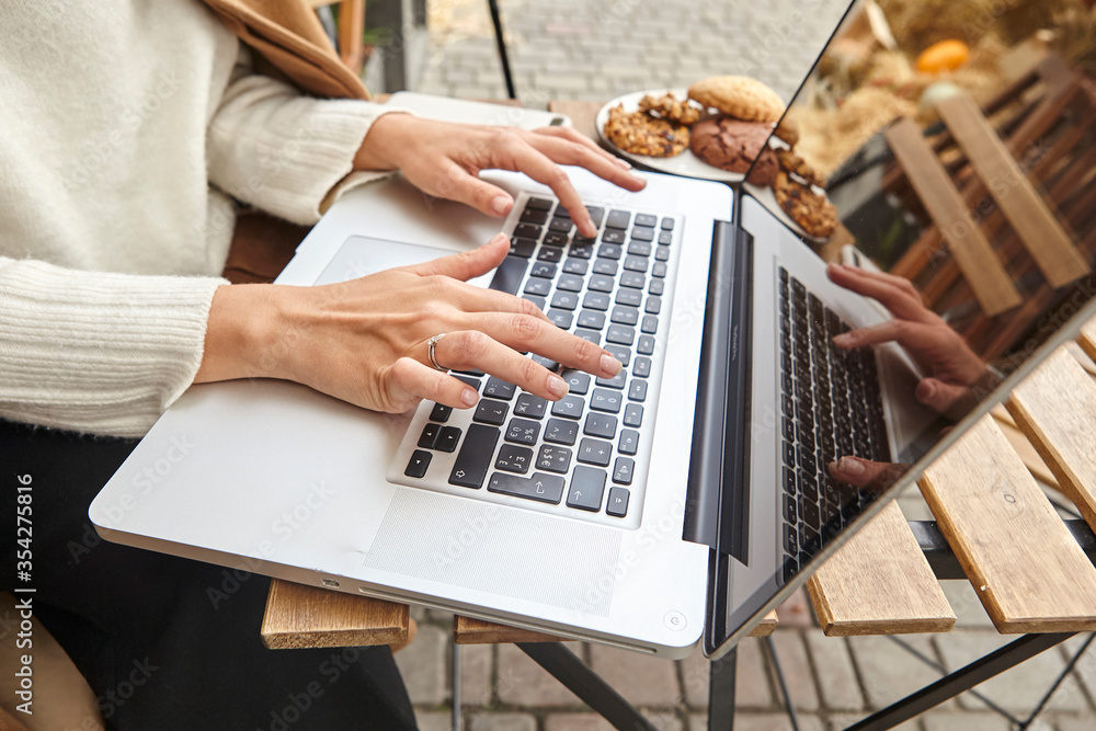 Fototapeta premium sweet dessert with a cup of coffee and female hands with a phone and laptop at the table