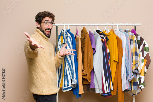 young cool berded man with clothes against flat wall photo